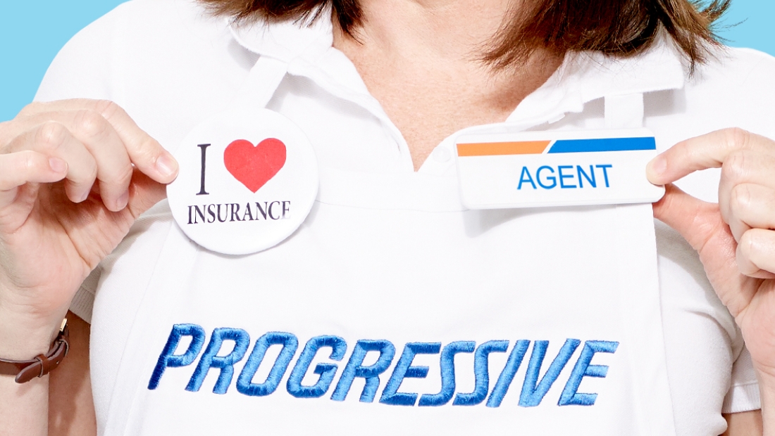 A close up of Flo's apron with a button that says I love insurance and a nametag that says Agent